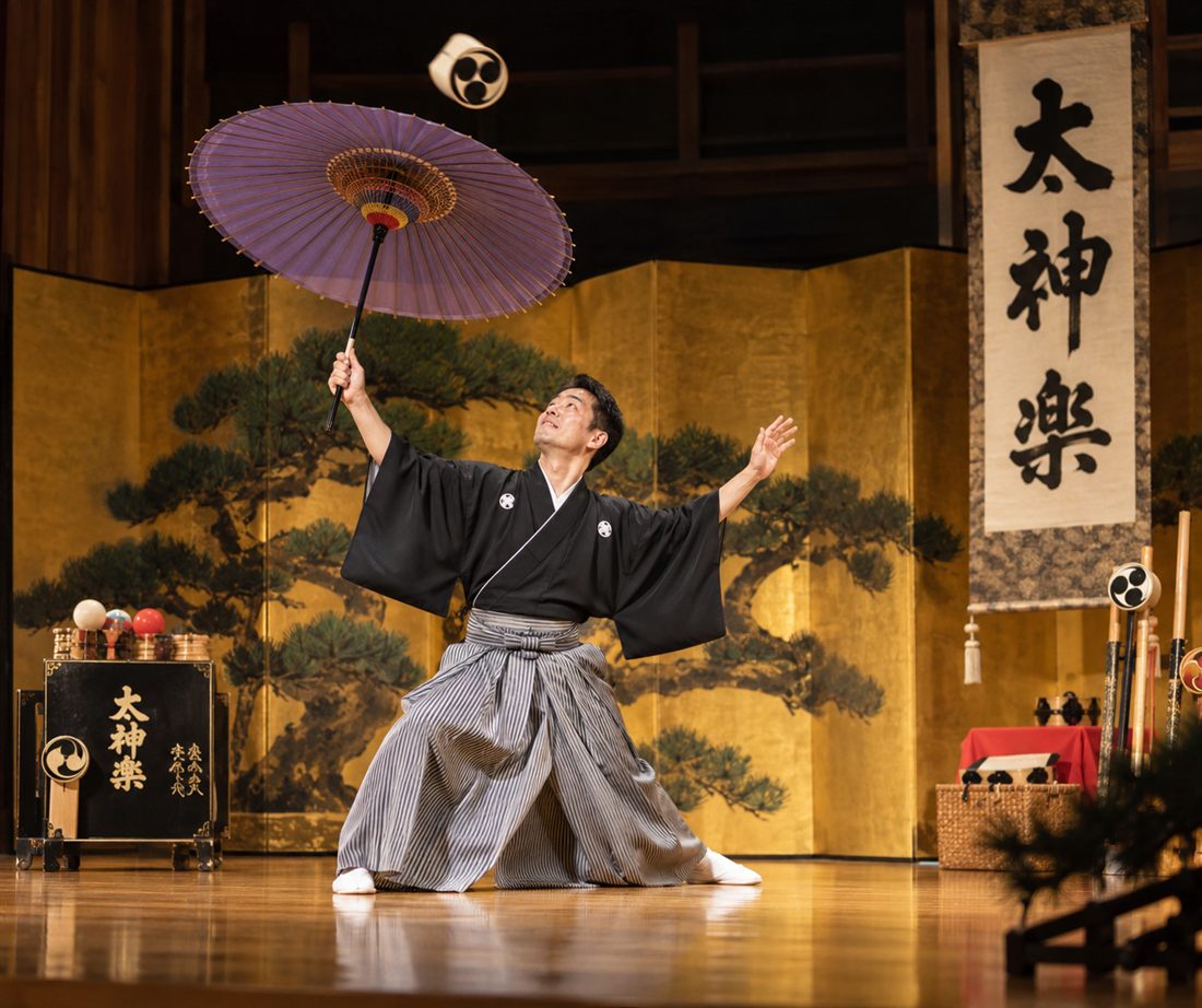 Daikagura performer balancing an umbrella, traditional Japanese performance art